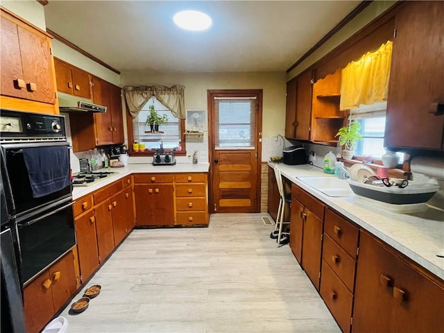 kitchen featuring white gas stovetop, sink, double oven, tasteful backsplash, and light hardwood / wood-style floors