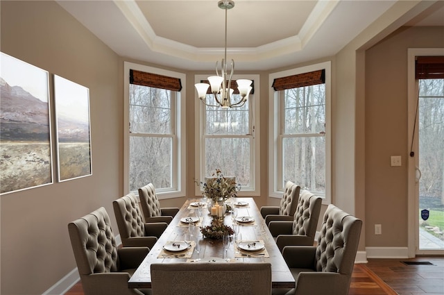 dining area featuring a tray ceiling, dark hardwood / wood-style flooring, ornamental molding, and an inviting chandelier