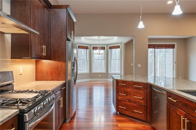 kitchen with backsplash, ventilation hood, decorative light fixtures, light stone counters, and stainless steel appliances