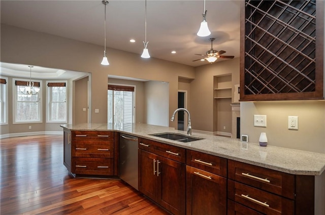 kitchen with stainless steel dishwasher, pendant lighting, light stone countertops, and sink