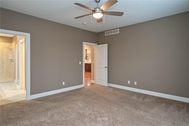 unfurnished bedroom featuring ceiling fan, ensuite bathroom, and light colored carpet