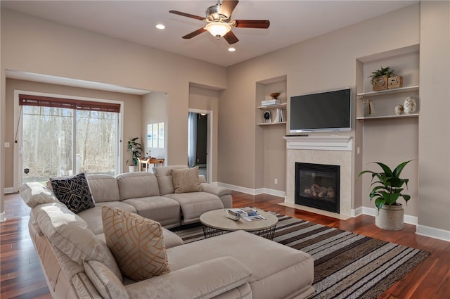 living room featuring built in shelves, dark hardwood / wood-style floors, and ceiling fan