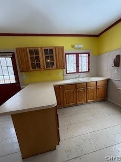 kitchen with plenty of natural light, crown molding, kitchen peninsula, and sink