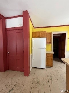 kitchen with crown molding, white fridge, and light wood-type flooring