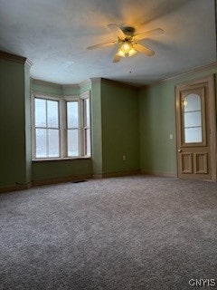 empty room featuring ceiling fan, carpet floors, and ornamental molding