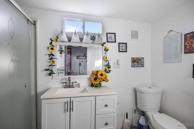 bathroom featuring vanity, toilet, and a shower with shower door