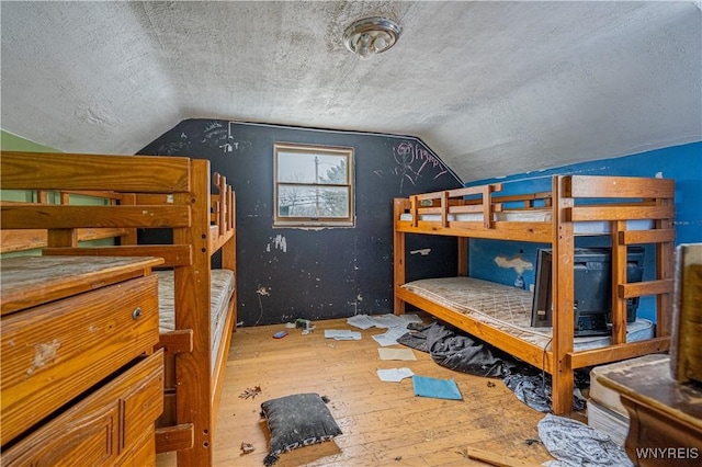 bedroom with hardwood / wood-style floors, lofted ceiling, and a textured ceiling