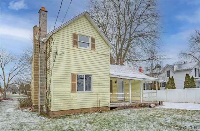 snow covered back of property featuring a lawn