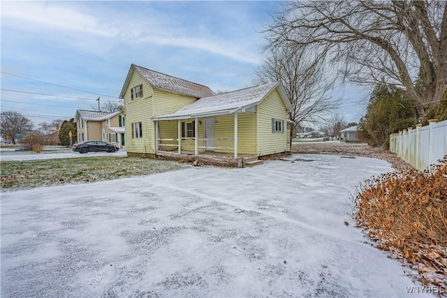 snow covered property with covered porch