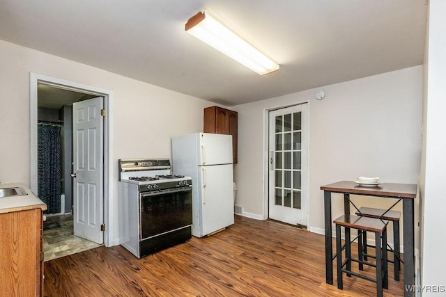 kitchen featuring wood-type flooring, white appliances, and sink