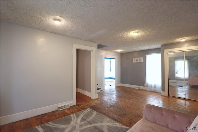 unfurnished living room featuring dark hardwood / wood-style flooring and a textured ceiling