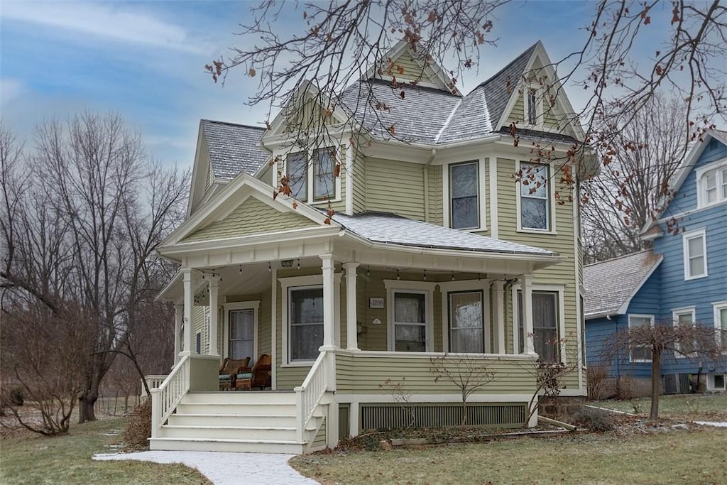 victorian house featuring a front lawn and a porch