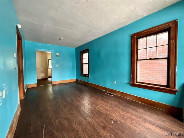 empty room featuring a textured ceiling and dark hardwood / wood-style floors