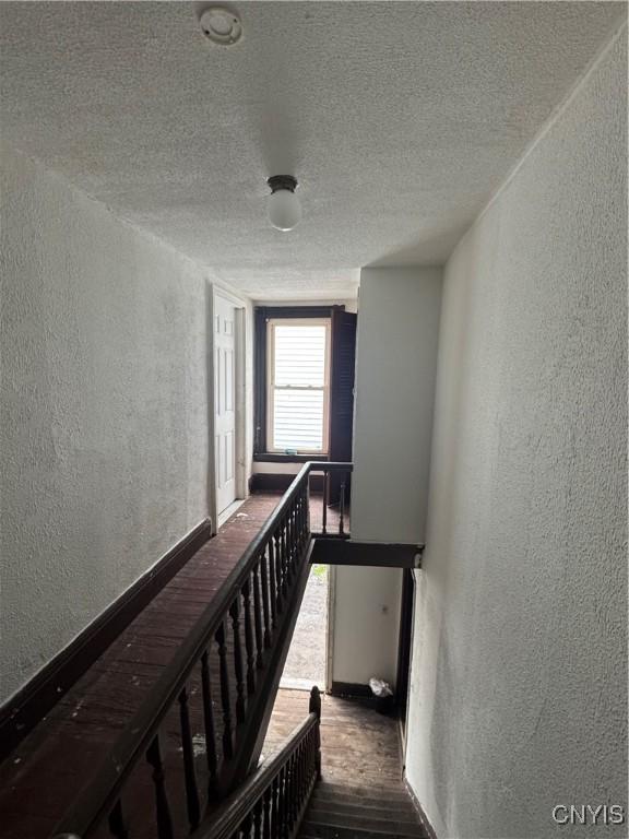 744 Jay St, Utica, NY 13501 - stairs with a textured wall, a textured ceiling, wood finished floors, and baseboards