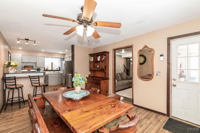 dining space with ceiling fan, sink, and light hardwood / wood-style flooring