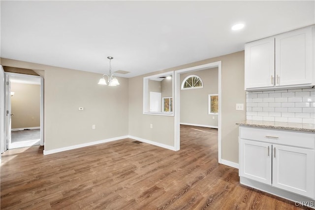 unfurnished dining area with wood-type flooring and a notable chandelier