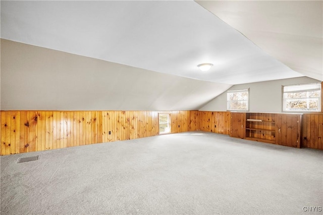 additional living space featuring carpet flooring, wooden walls, and lofted ceiling