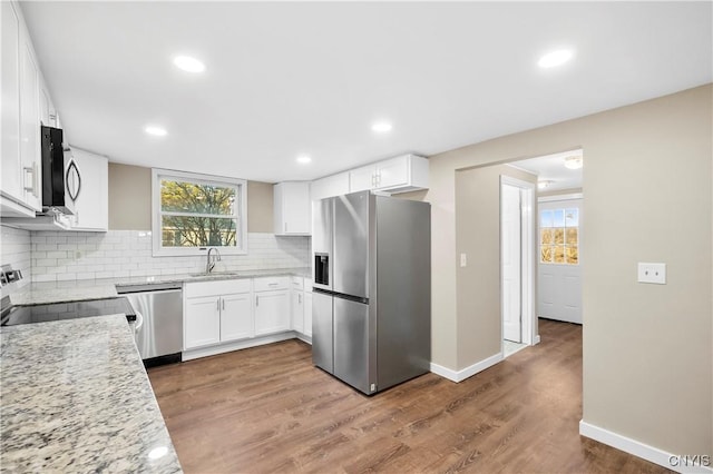 kitchen featuring white cabinetry, light stone countertops, tasteful backsplash, dark hardwood / wood-style flooring, and appliances with stainless steel finishes