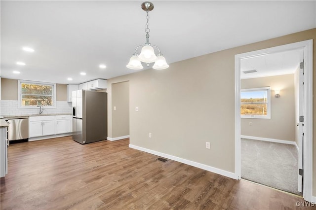 kitchen featuring a wealth of natural light, white cabinetry, tasteful backsplash, pendant lighting, and appliances with stainless steel finishes