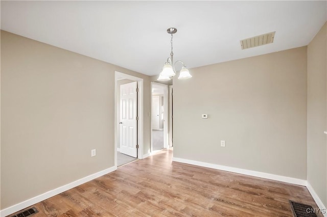 empty room with a chandelier and hardwood / wood-style flooring