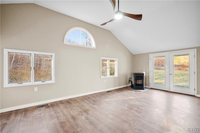 unfurnished living room with hardwood / wood-style floors, vaulted ceiling, a wood stove, and ceiling fan