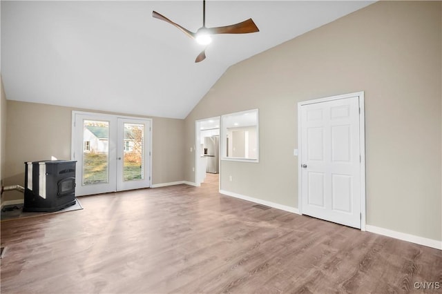 unfurnished living room with french doors, vaulted ceiling, ceiling fan, wood-type flooring, and a wood stove