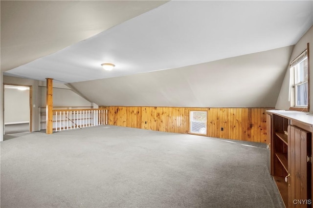 bonus room featuring plenty of natural light, vaulted ceiling, and dark colored carpet