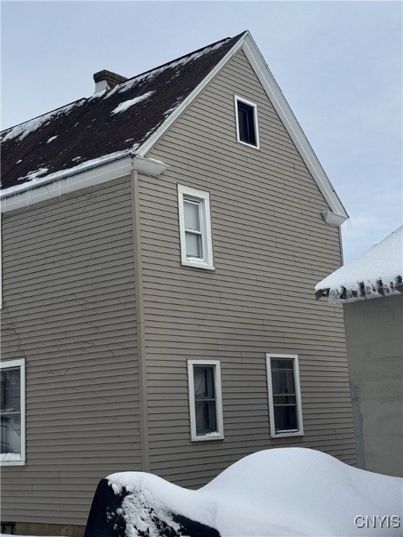 view of snow covered exterior featuring a chimney