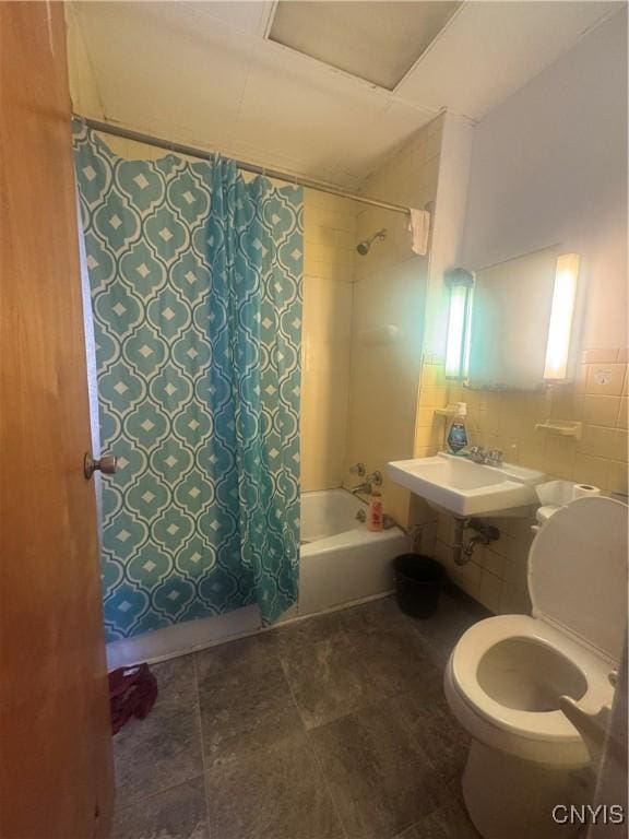 bathroom featuring shower / bath combo, a sink, toilet, and tile walls