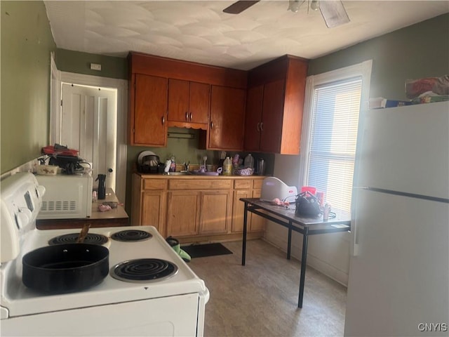 kitchen featuring white appliances, ceiling fan, brown cabinets, light floors, and a sink