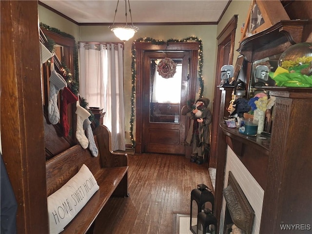 foyer entrance with ornamental molding and dark wood-type flooring