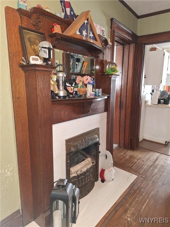 details with hardwood / wood-style flooring, a brick fireplace, and ornamental molding