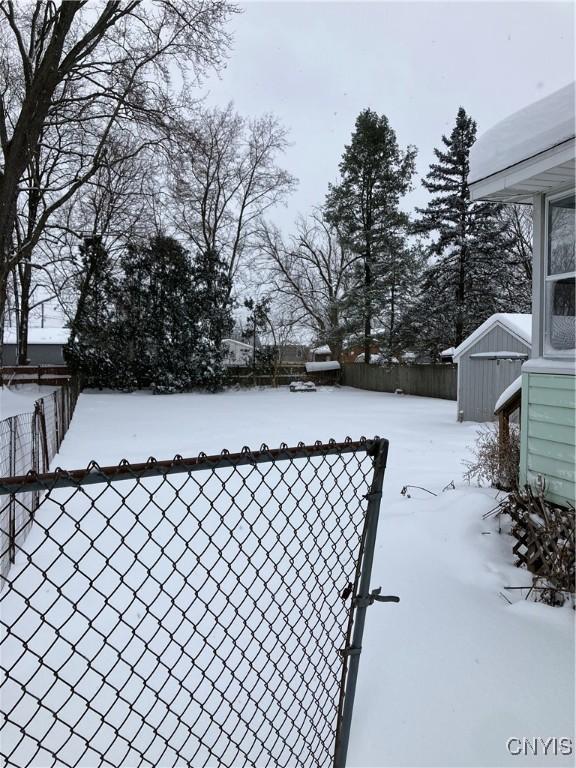 snowy yard featuring a storage shed