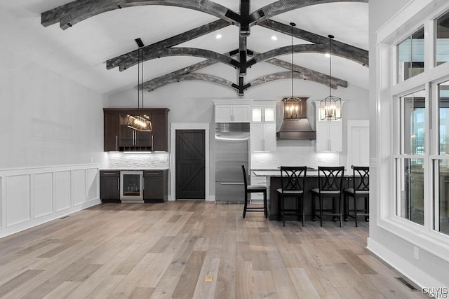 kitchen with backsplash, premium range hood, white cabinets, decorative light fixtures, and stainless steel built in refrigerator