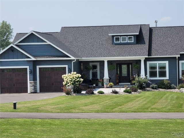 craftsman inspired home with a garage, covered porch, and a front yard