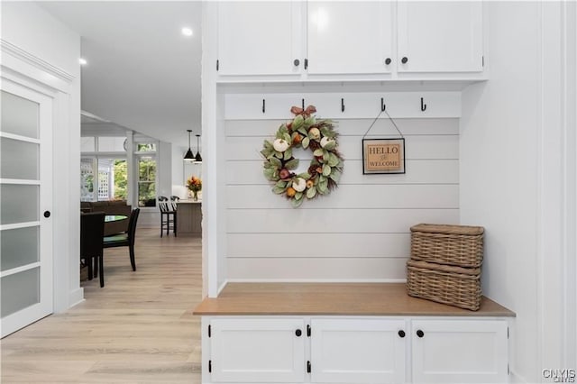 mudroom featuring light hardwood / wood-style flooring and wooden walls