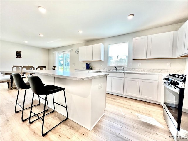 kitchen featuring white cabinets, a center island, light hardwood / wood-style floors, and gas range