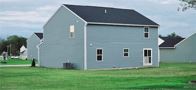 rear view of property featuring a yard and central air condition unit