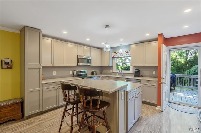 kitchen with sink, pendant lighting, a breakfast bar, a kitchen island, and appliances with stainless steel finishes