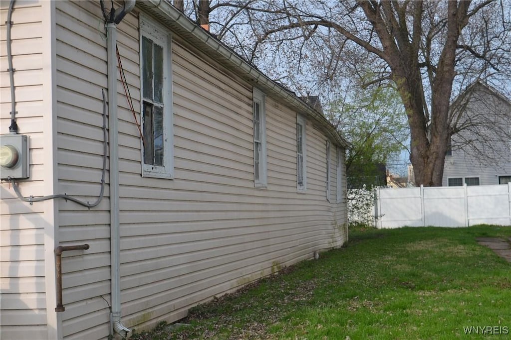 view of property exterior featuring a lawn and fence