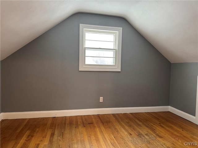 additional living space with wood-type flooring and vaulted ceiling