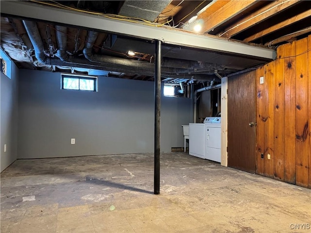 basement featuring washer and clothes dryer and wooden walls