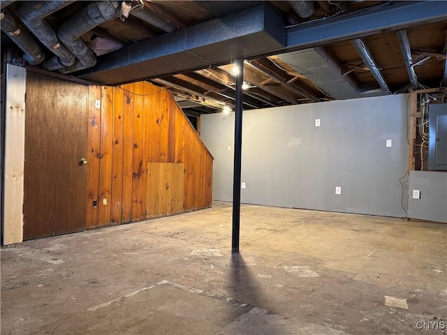 basement featuring wooden walls and electric panel