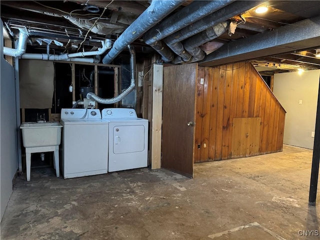 basement with sink, washing machine and clothes dryer, and wood walls