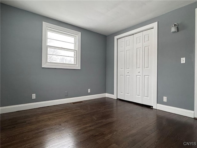 unfurnished bedroom featuring dark wood-type flooring and a closet