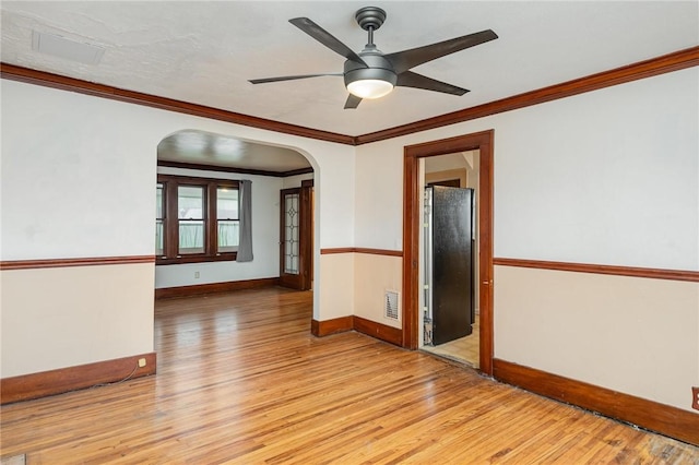 empty room featuring ceiling fan, light wood-type flooring, and crown molding