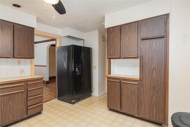 kitchen featuring decorative backsplash, ceiling fan, black fridge, and a textured ceiling