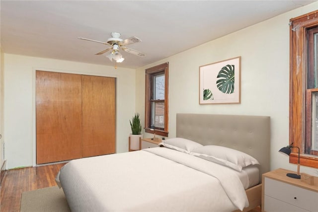 bedroom with ceiling fan, dark wood-type flooring, and a closet