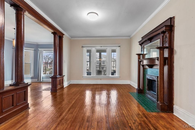 unfurnished living room with a wealth of natural light, crown molding, a fireplace, and ornate columns