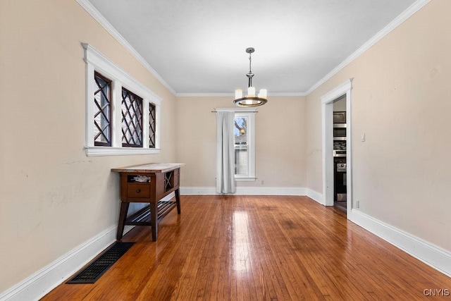 interior space featuring ornamental molding, hardwood / wood-style flooring, and a notable chandelier